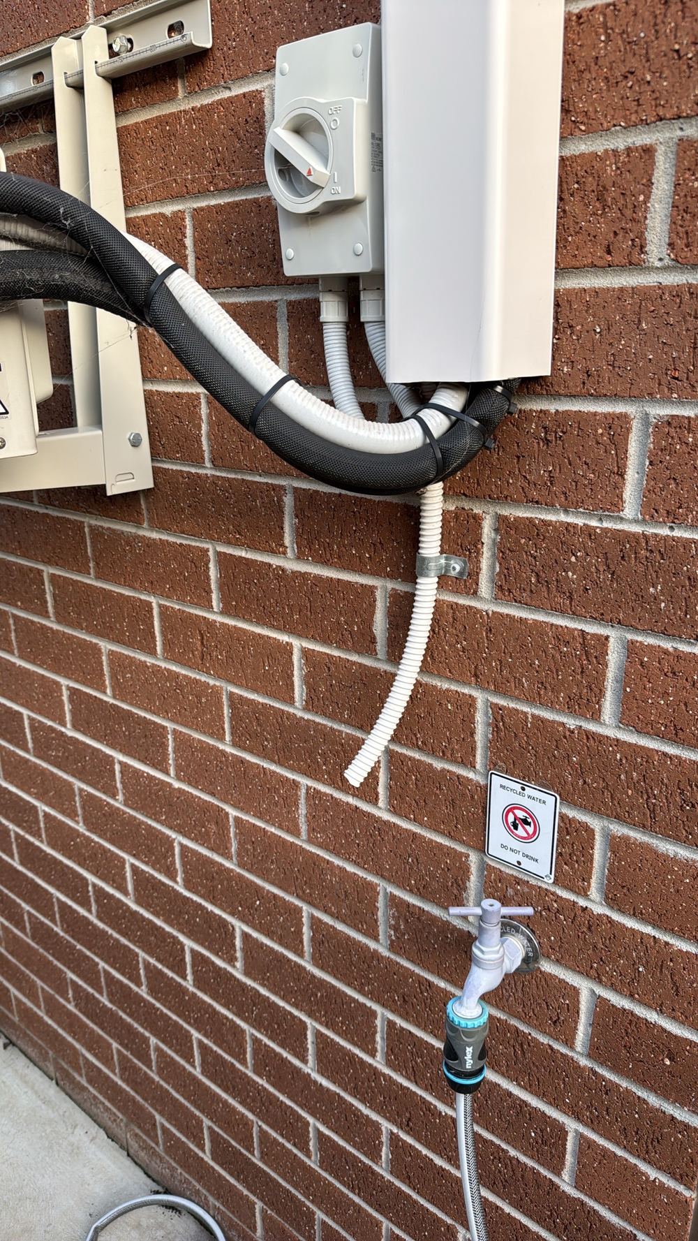 Air conditioner condensate dripping onto the soil beside the wall, found during a building and pest inspection in Officer