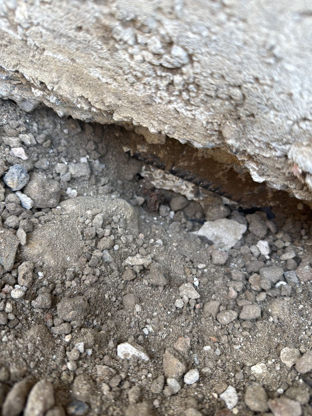 Slab edge chipped away during services work, leaving reinforcement exposed, found during a pre-handover inspection in Officer